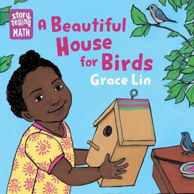 A smiling dark skinned child wearing a yellow flowered t-shirt holds a wooden bird house