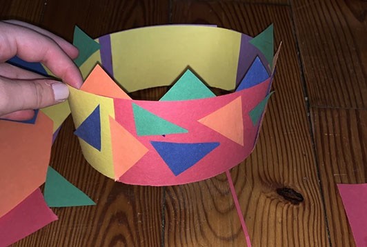Crown made out of a circular band of paper with colorful paper triangles glued all around.