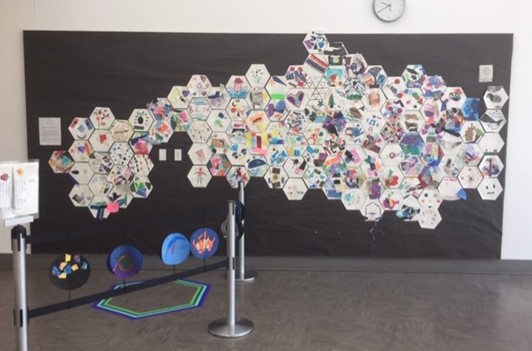 A mural made from hexagon-shaped collages covers a large bulletin board.