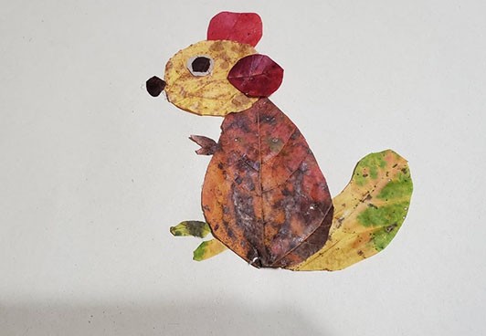 Collage of a chipmunk made from a variety of red, yellow, and brown leaves. 