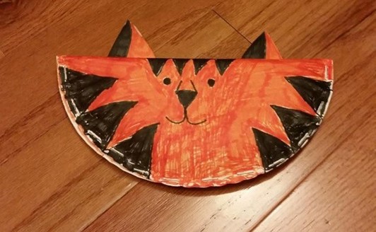paper plate folded in half and stapled with a tiger face drawn on with markers