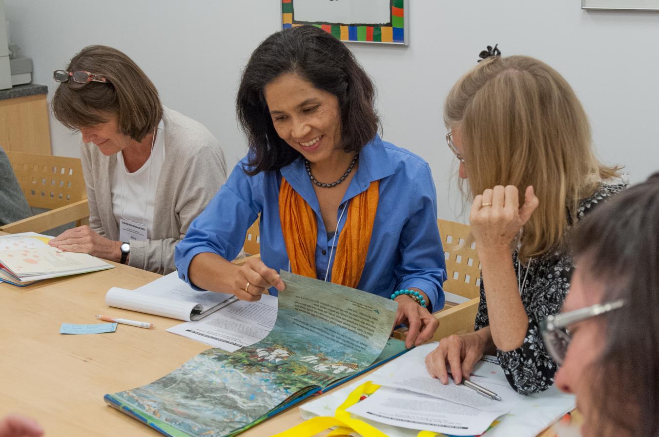 Educators at a table looking at and discussing picture books