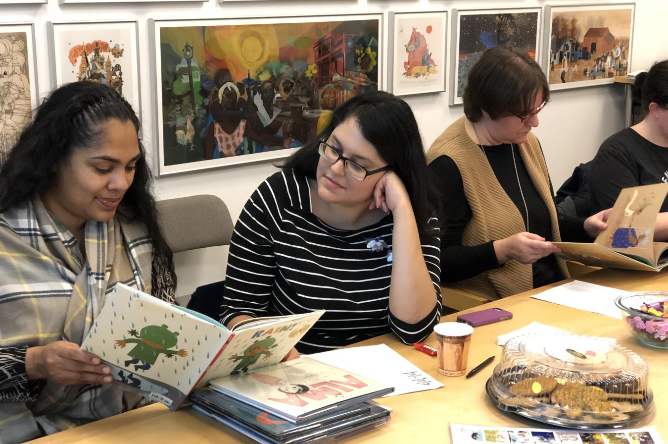 Two women reading a book together at a table