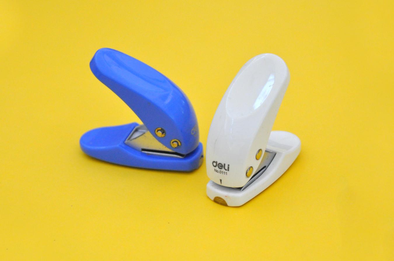 Two small hole punchers that sit flat on a table surface, with a push-down lever to activate.