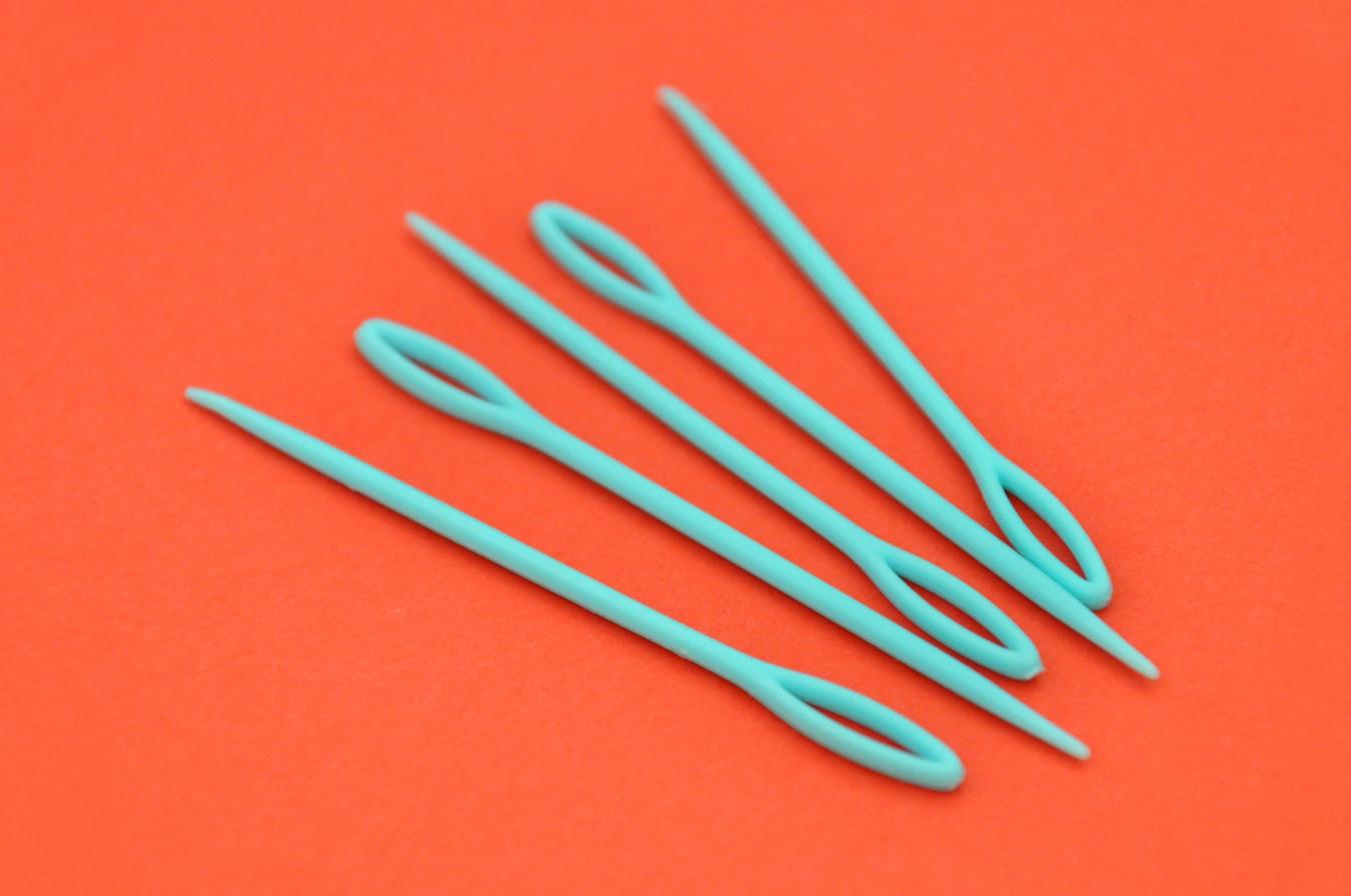 Five large plastic needles placed next to each other on a table.