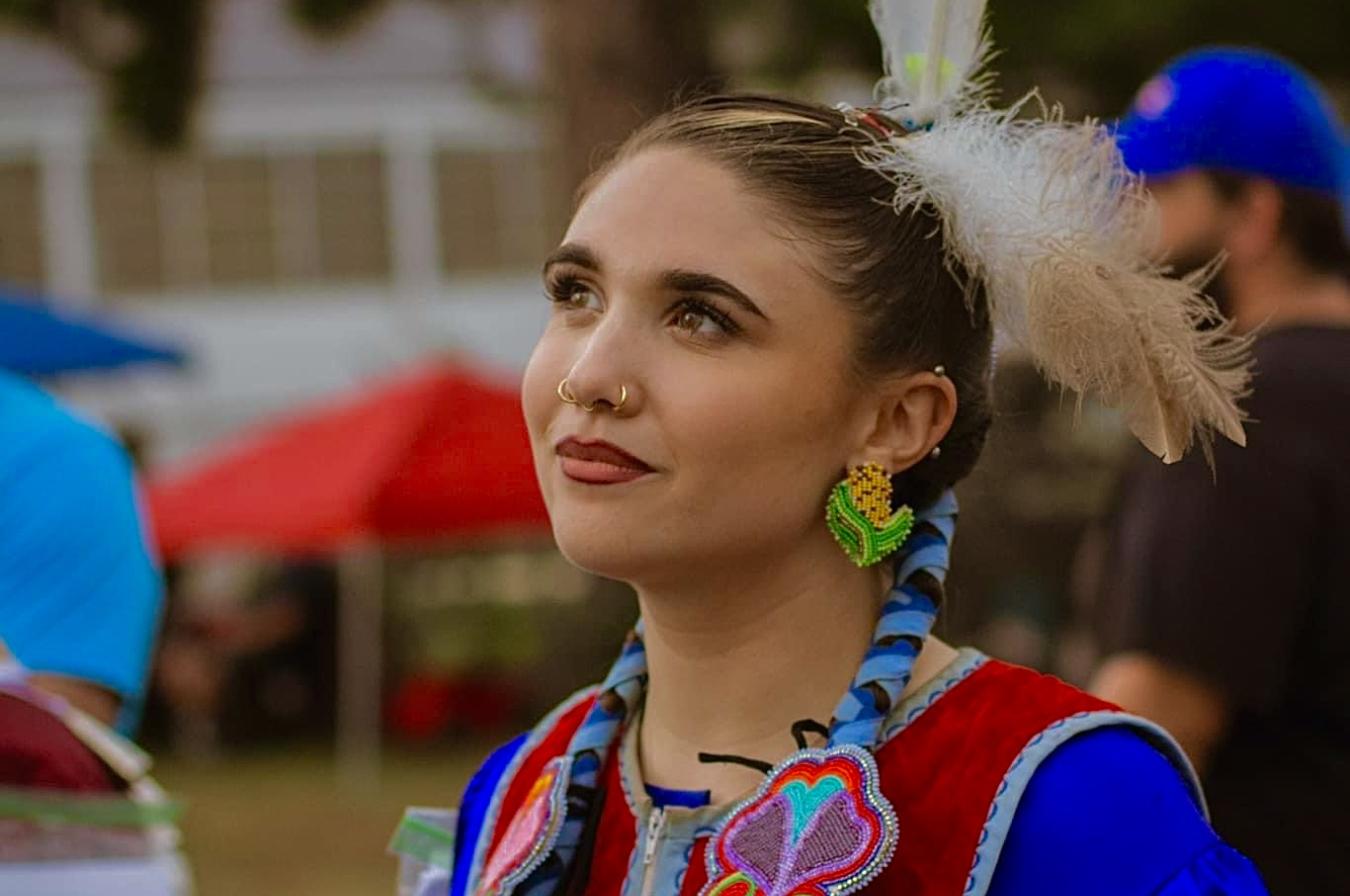 Young woman in blue dress with braded hair with feathers