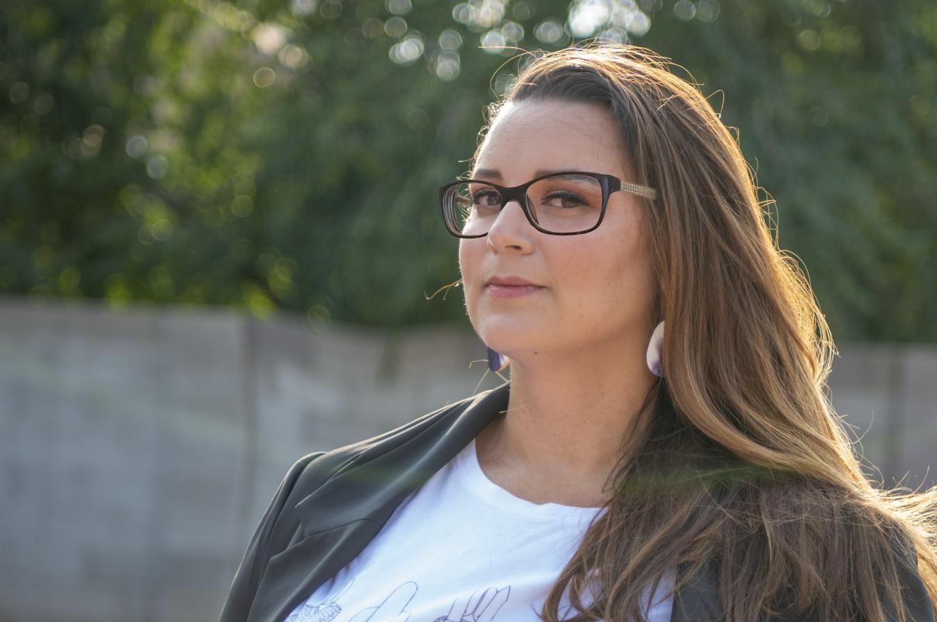 woman with long brown hair, glasses, white t-shirt and black jacket