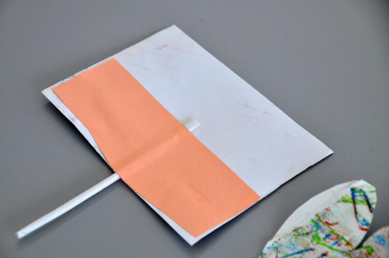Rectangle of paper attached to a straw with another paper strip