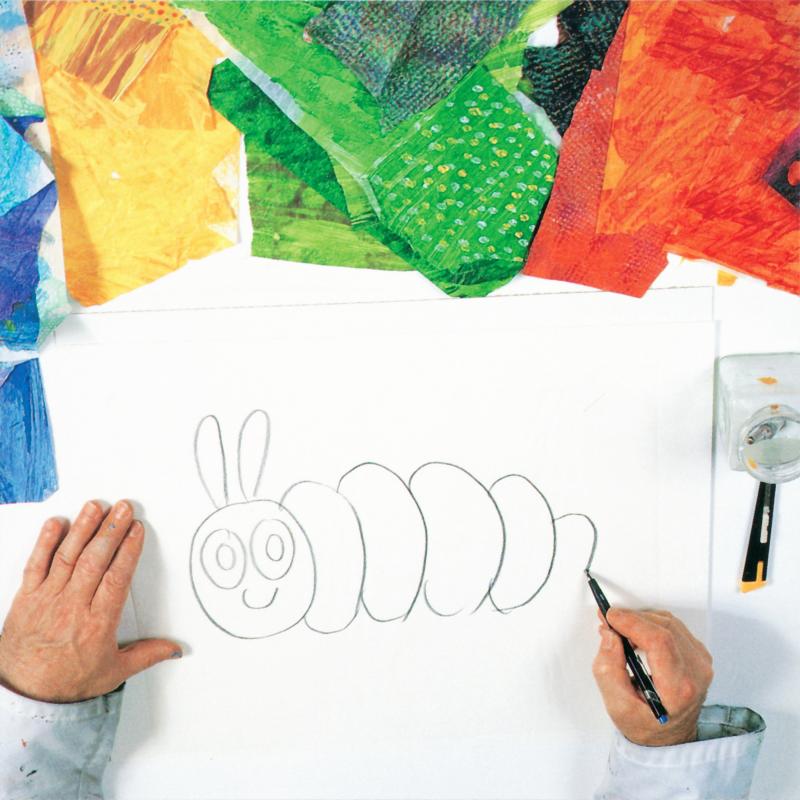 hand holding a pencil completing an outline of the Very Hungry Caterpillar on tracing paper