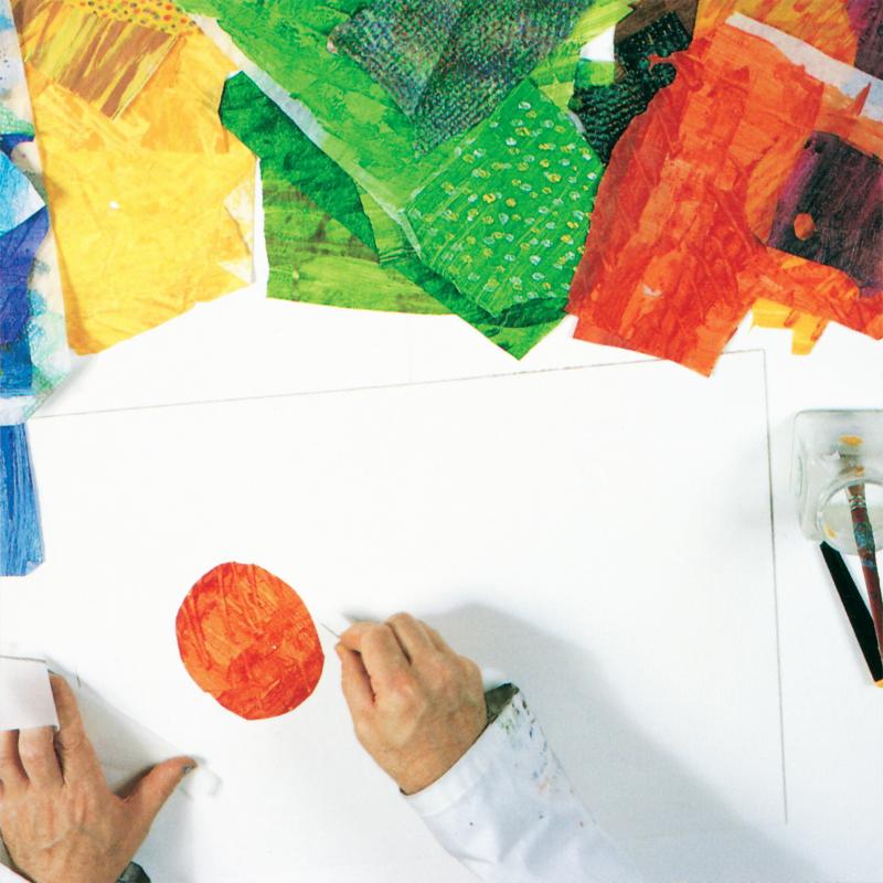 Hand glueing red tissue paper circle on white paper. Blue, yellow, green, and red tissue papers are in the background.