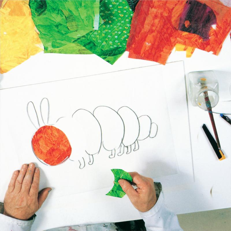 Red oval tissue paper with tracing paper caterpillar drawing and hand holing cut green tissue paper