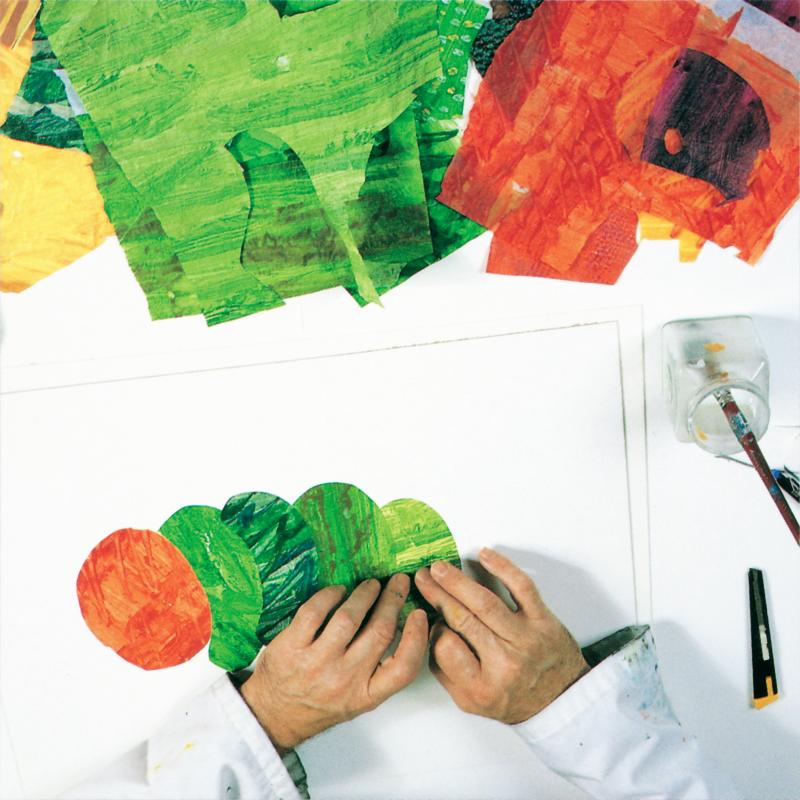 two hands placing green tissue paper shape next to three other greed tissue paper shapes and a red tissue paper oval to create caterpillar collage