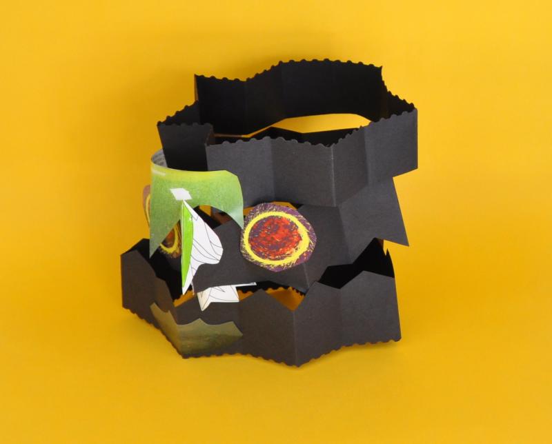 A mask made from folded paper with collage details