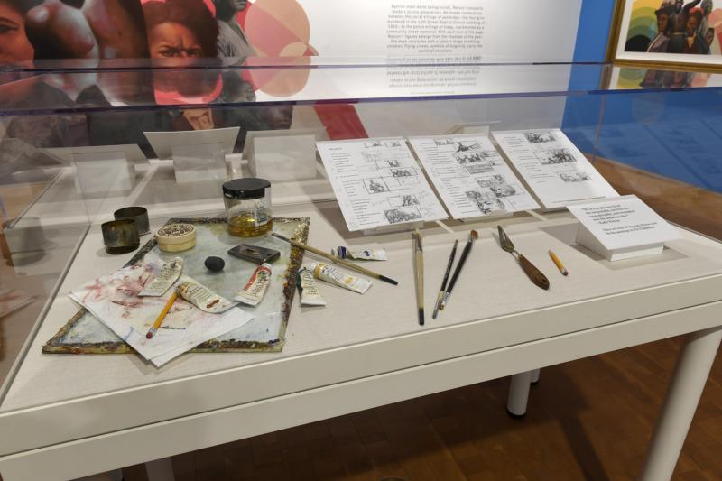 Photograph of painting tools and sketches in case.