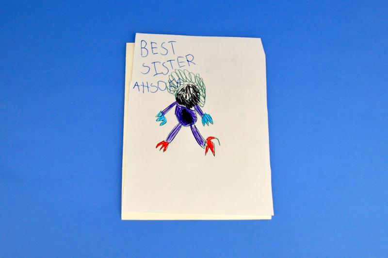 A page from an accordion fold book with the words "best sister" and a drawing.