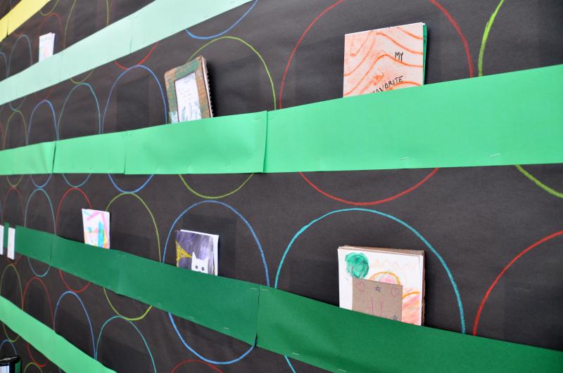 A close-up of the Art Studio bulletin board showing construction paper pockets with accordion fold books inside.
