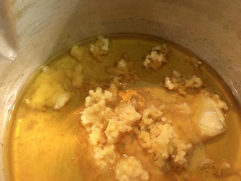 Wax pellets and cocoa butter coins halfway melted in the pot.