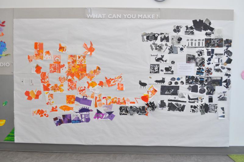 A wall installation with orange, purple, and black collages spreading across it.