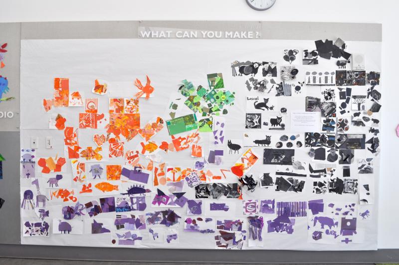 A wall installation with orange, purple, black, and green collages spreading across it.