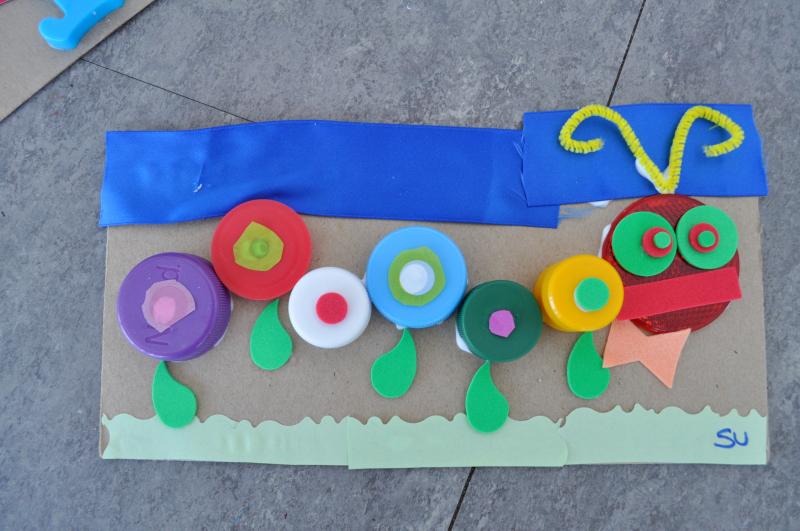 A mixed-media caterpillar collage with lots of colorful layered circular caps.