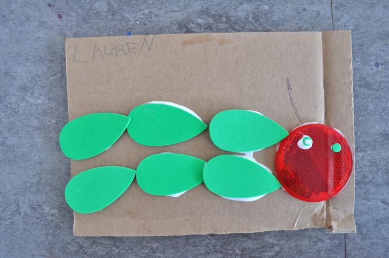 An abstract caterpillar collage made from foam pieces and a plastic reflector.