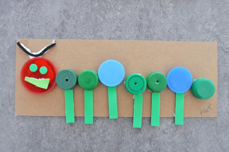 An artwork of a caterpillar made out of bottle caps and self-adhesive foam.