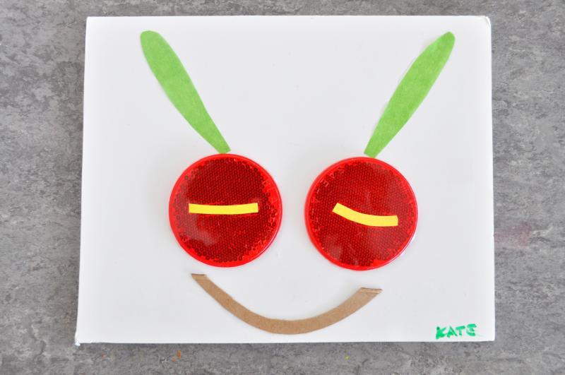 A caterpillar face made out of papers and circular plastic reflectors.