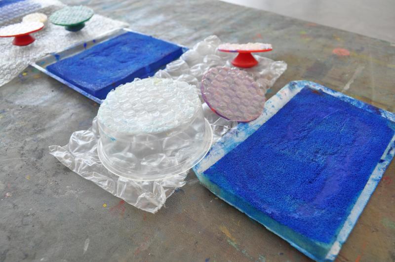 Stamp pads with blue paint on them next to stamps with bubble wrap taped to them.