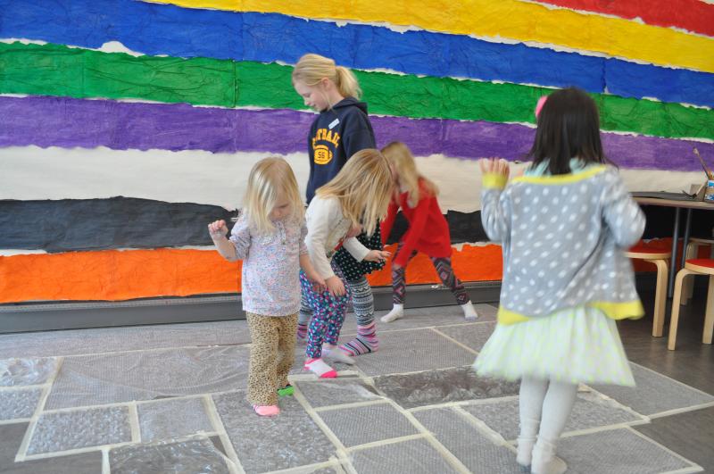 A group of young guests walking on top of the bubble wrap taped to the floor.