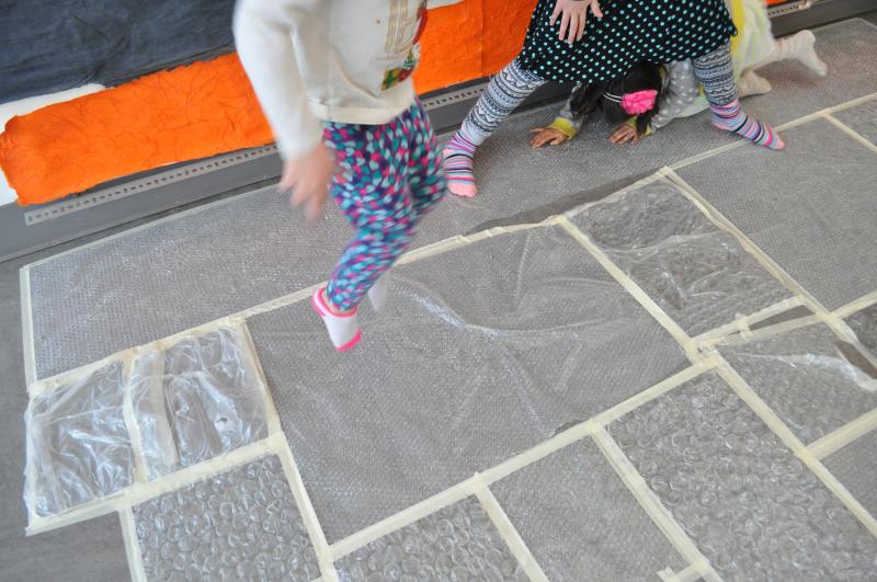 A young guest mid-air jumping on top of bubble wrap sheets.