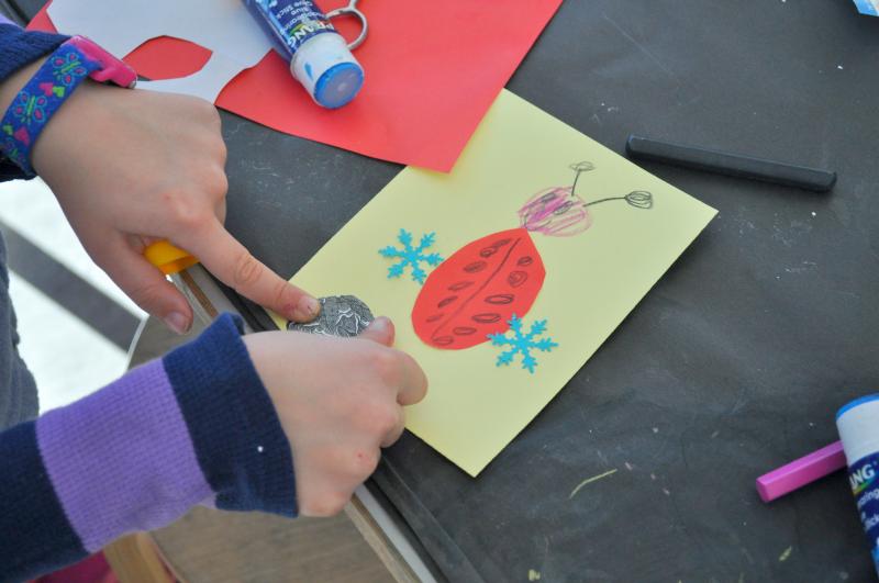 A child collages with colorful papers to make a ladybug on a valentine card.