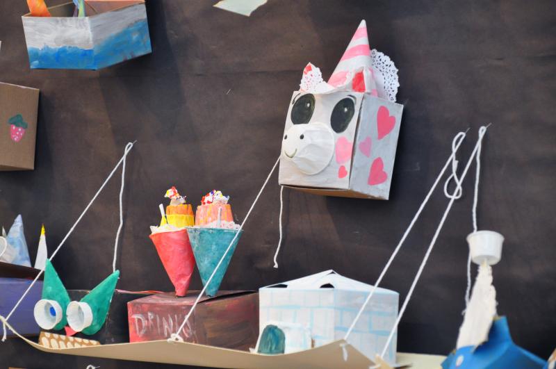 Sculptures in the display, a pink and white unicorn with hearts, a creature with rows of teeth, and a shaved ice drink stand.