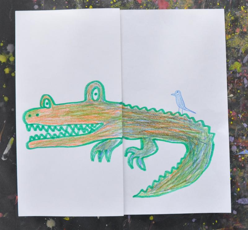Drawing of a crocodile on a square sheet of paper, there is a blue bird sitting on the animals back