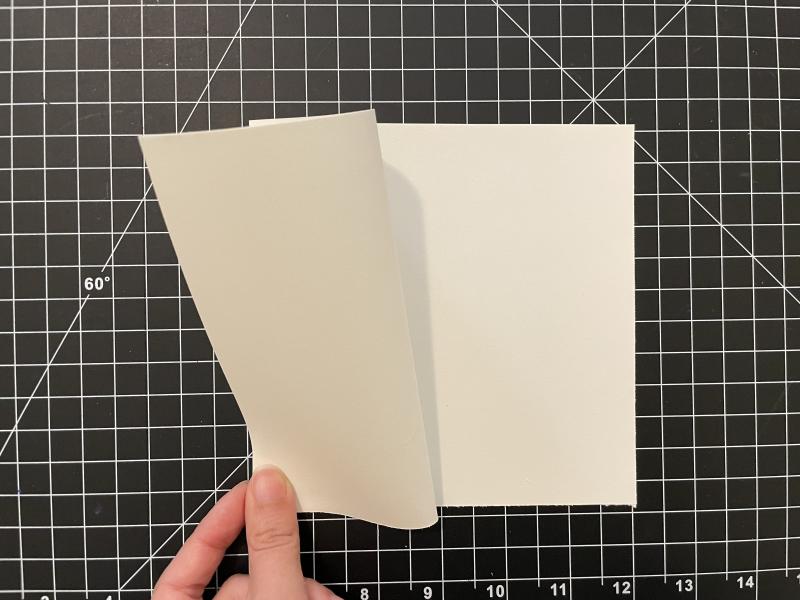 The cover of the book is being folded back in half. The corners of the page are being lined up to the spine of the paper.