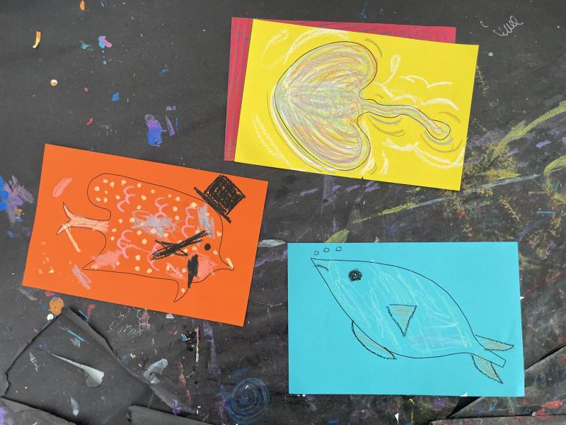 Brightly colored papers with guest drawn colorful fish and creatures.