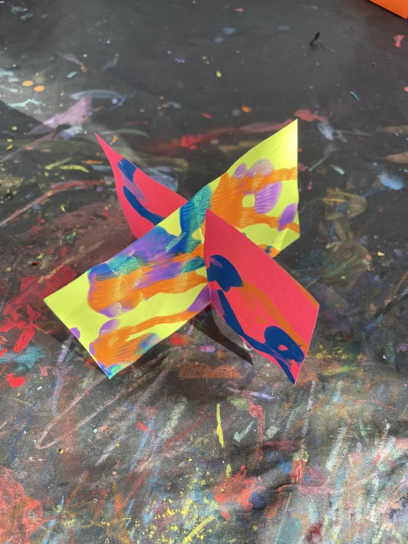 Two sheets of paper cut halfway and slipped together in a notch. Creating a 'X' shape.