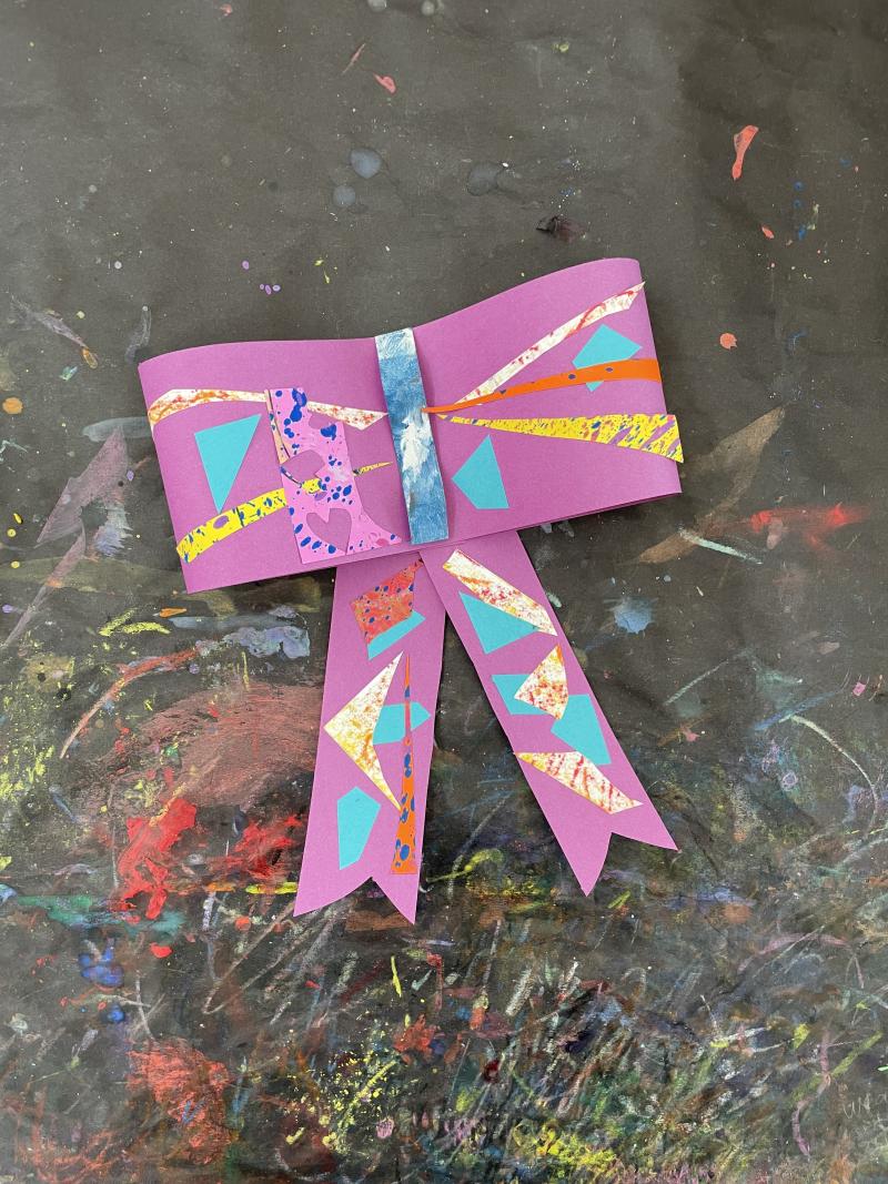 Purple paper bow with colorful paper triangle decorations.