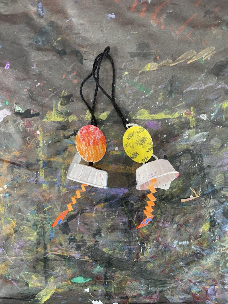 Yarn looped with paper objects dangling for paper earrings.