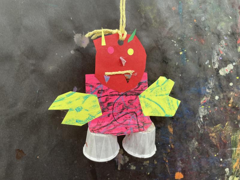 Paper objects and collage papers pieced together to create a colorful dragon puppet.