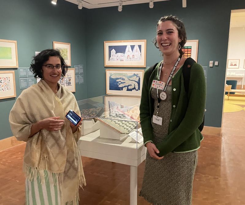 two women smiling at the camera standing in an art gallery