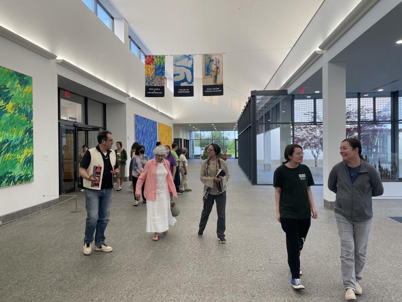 group walking in Musseum great hall with exhibition banners in the background and Eric Carle murals on the wall