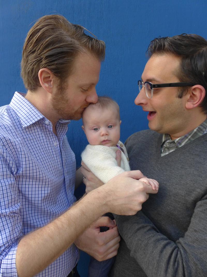 photograph of dads holding baby.