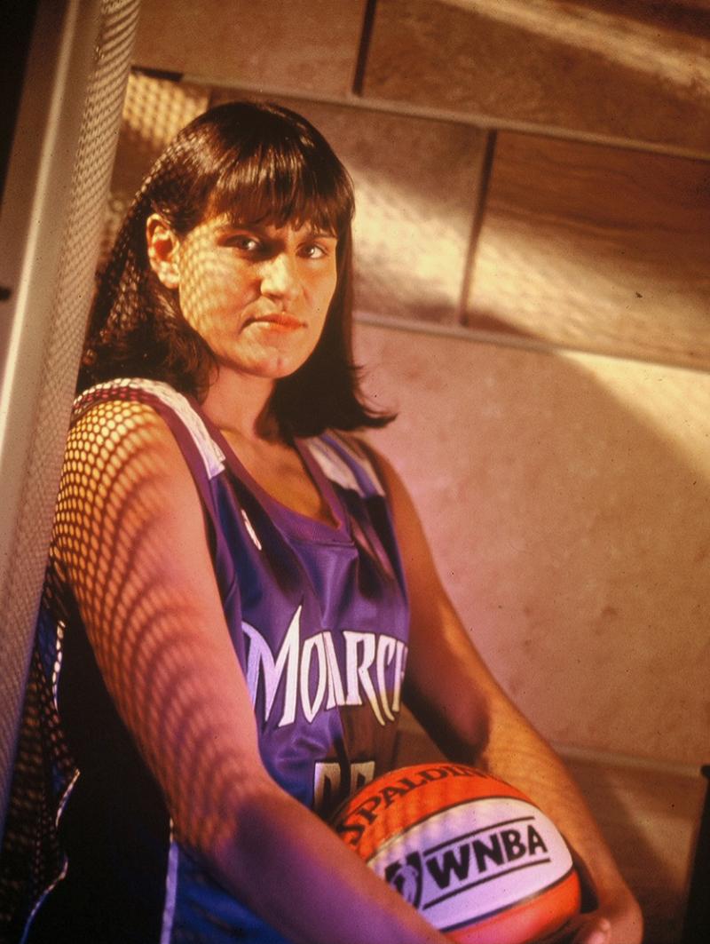 Photograph of woman in jersey holding basketball.