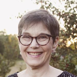 a white woman wearing glasses and smiling