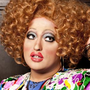 a white drag queen with tall red curly hair, looking fabulous