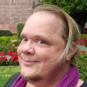 Alex Gino wearing a purple scarf and smiling.