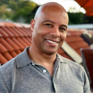 picture of a black man smiling in a grey-collared shirt