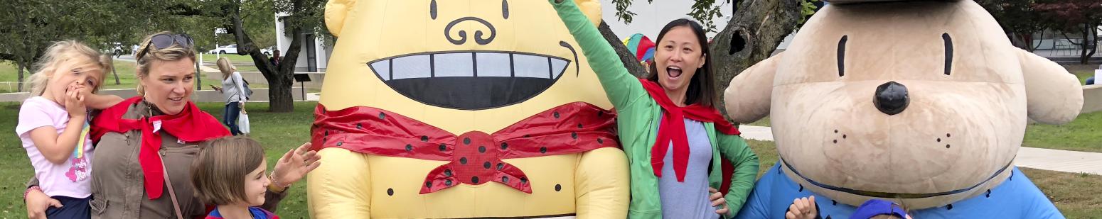 Visitors posing for group photo with Captain Underpants and Dog Man at an event..