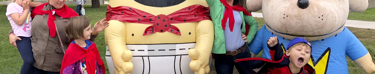 Visitors posing for group photo with Captain Underpants and Dog Man at an event..