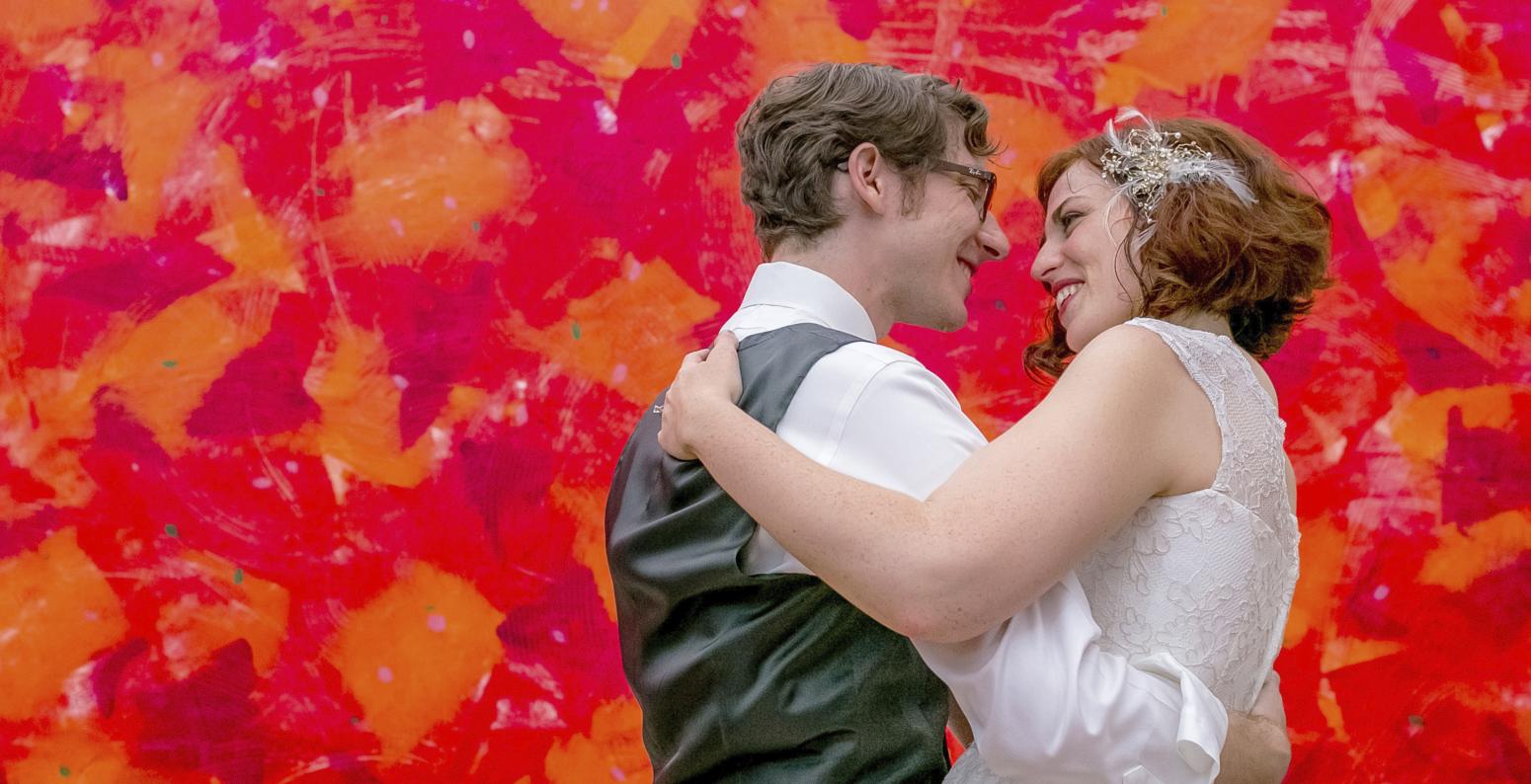 Wedding couple standing in front of a red painting.